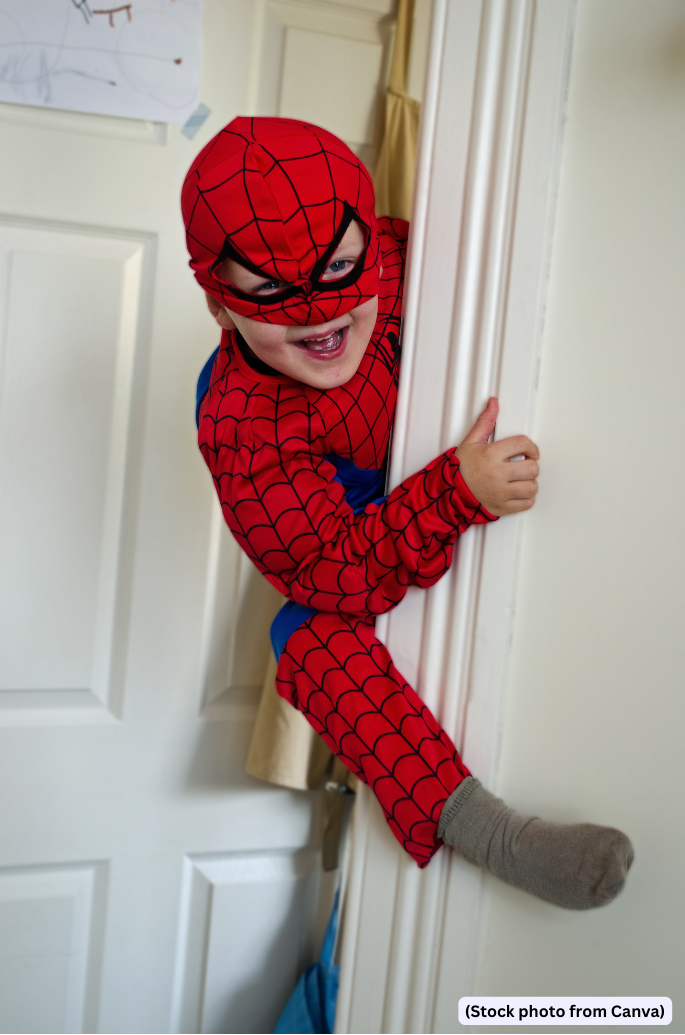 Kid pretends to climb a wall wearing a Spider Man costumer (Stock photo from Canva)